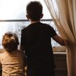A brother and sister through single parent adoption look out the window.