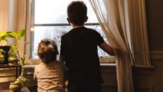 A brother and sister through single parent adoption look out the window.