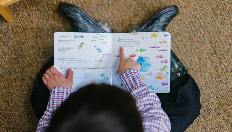 A boy reads an adoption children's book