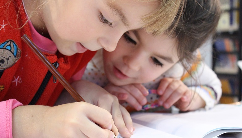 Two girls work together on a project during adoption classes.