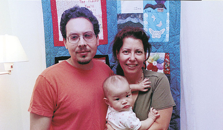 A family in front of their keepsake quilt