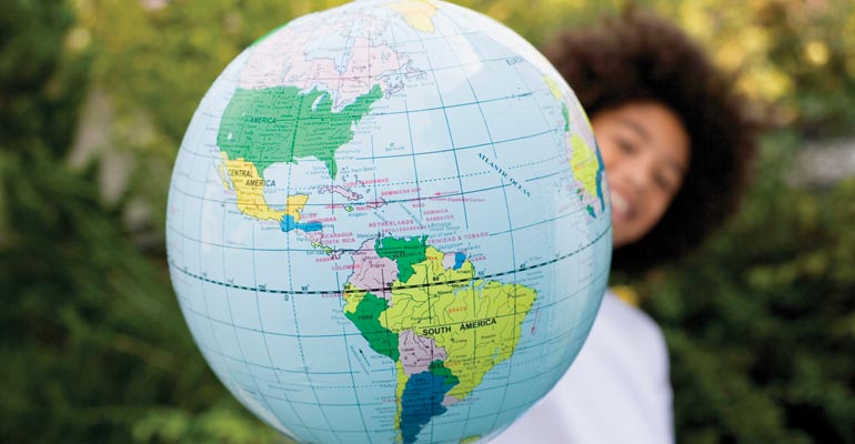 A child with a globe, representing a homeland trip