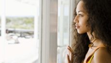 A woman stares out the window, contemplating the different types of adoption.