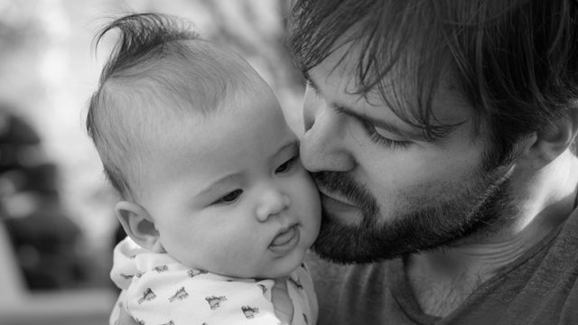 A man holds his baby after adopting a child of a different race.