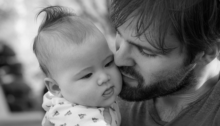 A man holds his baby after adopting a child of a different race.