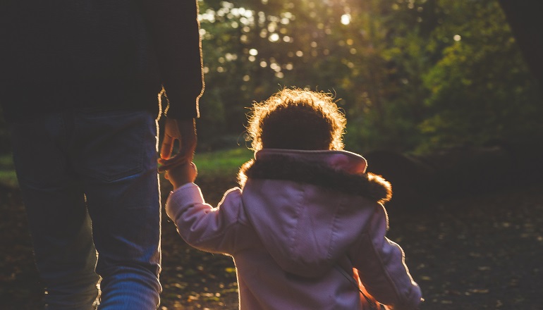 A dad walks in the forest with his daughter after adopting after age 50.