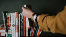 A woman picks up an adoption book from a bookshelf.