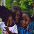 Three children sit on a swing.