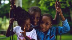 Three children sit on a swing.