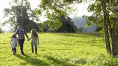 Family walking up a grassy hill together having a talk about adoption