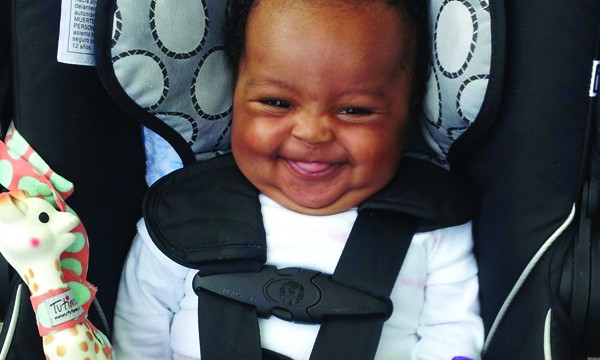 A baby in a car seat happy about childproofing