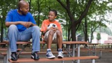 Parenting teens: a dad sits outside with his son at a picnic table