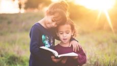 Two girls read about their birth culture together