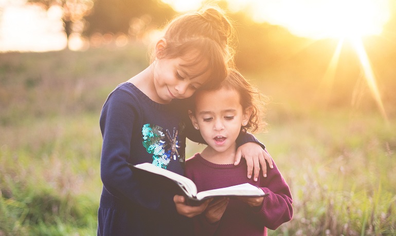 Two girls read about their birth culture together