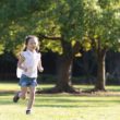 A resilient girl runs outside in a park.