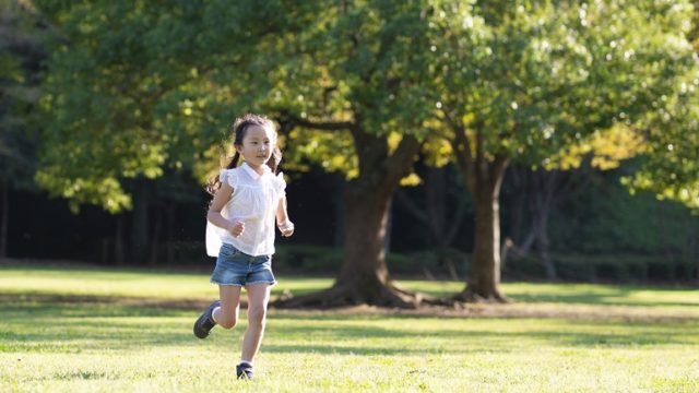 A resilient girl runs outside in a park.