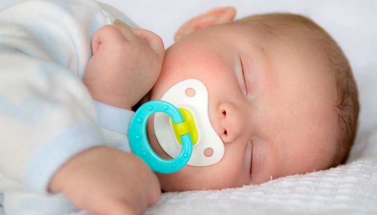 Infant baby boy sleeping peacefully with pacifier