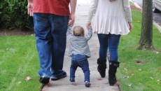 A newly formed family walking down the street, after the parents successfully navigated realtionships with expectant mothers