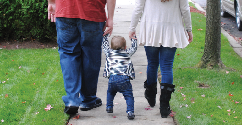 A newly formed family walking down the street, after the parents successfully navigated realtionships with expectant mothers