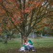 A woman sits in a park, breastfeeding an adopted baby