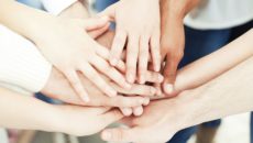 A group of adults put their hands in a circle after starting an adoptive parents support group