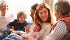 new mother talking to her father about open adoption as the new grandparents admire newborn baby