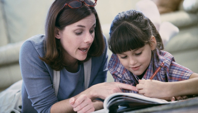 Mother assisting daughter with homeschooling work