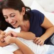 Mother And Son Lying In Bed Together Looking At Each Other Laughing. One example of connecting with kids.