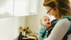 Adoptive mother wears newly adopted baby in baby carrier to help with bonding and adjustment