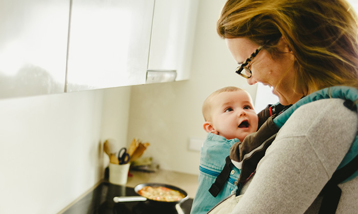 Adoptive mother wears newly adopted baby in baby carrier to help with bonding and adjustment