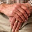 the hands of an older parent holding a walking stick