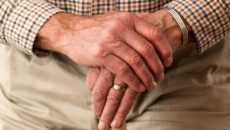 the hands of an older parent holding a walking stick