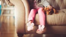 A child sits on the couch and wants privacy, a natural phase of the stages of childhood