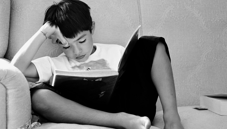 A grade school age boy reading books on adoption