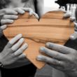 A group of people stand together, holding a wooden heart after adoption reunions