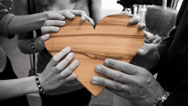 A group of people stand together, holding a wooden heart after adoption reunions