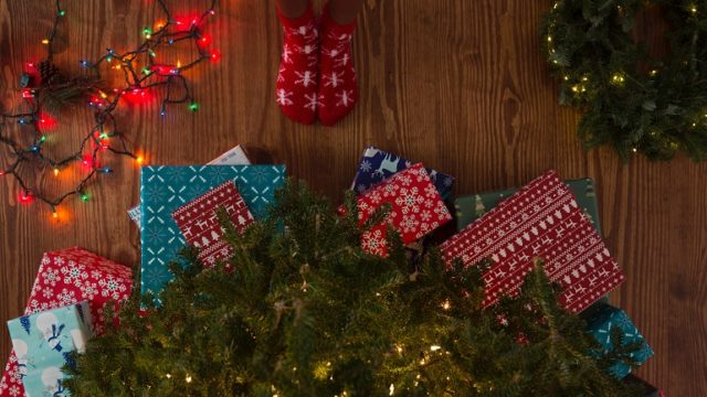 An adoptive mom stands in front of a pile of Christmas gifts