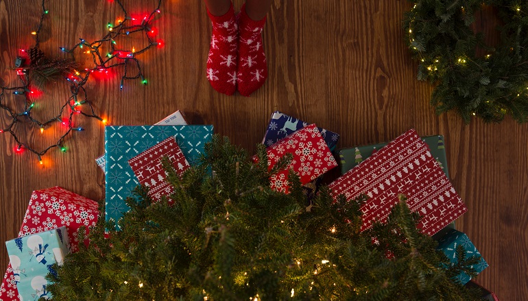 An adoptive mom stands in front of a pile of Christmas gifts