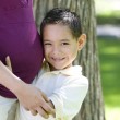 A young boy, adopted from Guatemala, hugging a woman's pregnant belly