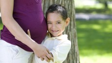A young boy, adopted from Guatemala, hugging a woman's pregnant belly