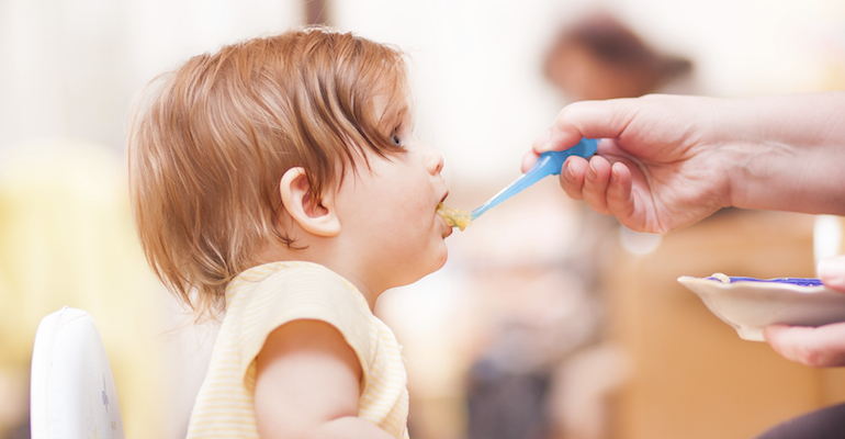 A parent feeding their child with tips learned from Love Me, Feed Me