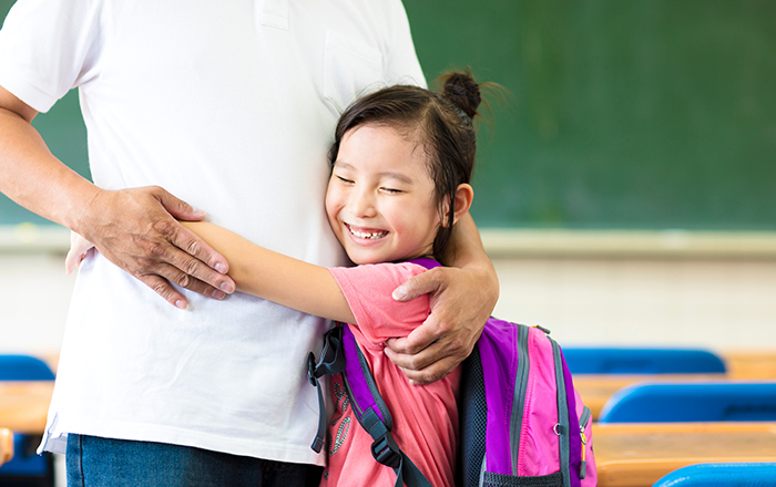 Girl hugging father in her inclusive, adoption-friendly classroom