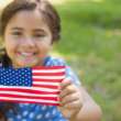 a girl who was adopted internationally but is now a U.S. citizen holds an American flag
