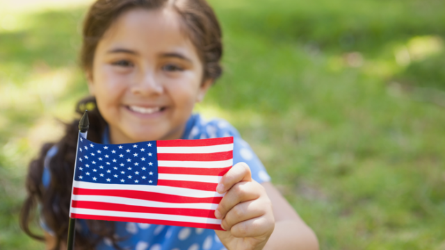 a girl who was adopted internationally but is now a U.S. citizen holds an American flag