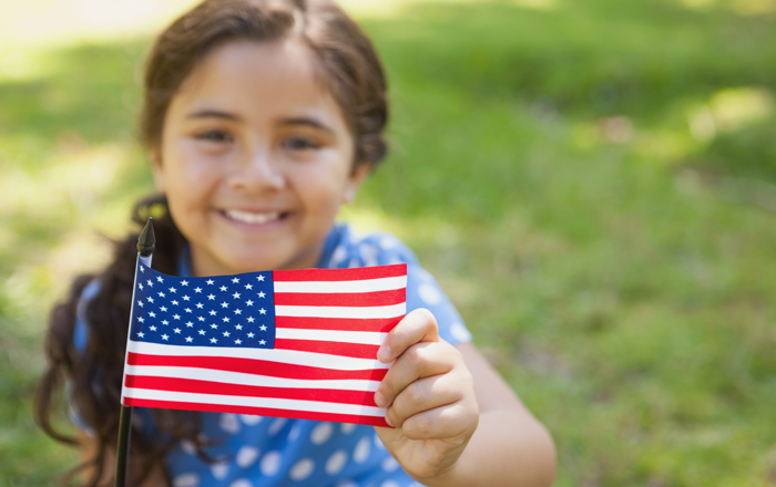 a girl who was adopted internationally but is now a U.S. citizen holds an American flag