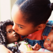 An African-American girls plays with two dolls that reflect her race