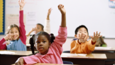 diverse adopted children raising their hands in a classroom, feeling safe at school