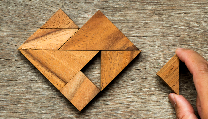 father's hand placing missing piece in wooden heart tangram puzzle, representing healing after older child adoption