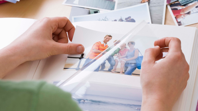 a woman looks through an album, holding a photo of her biological brother from one of his visits