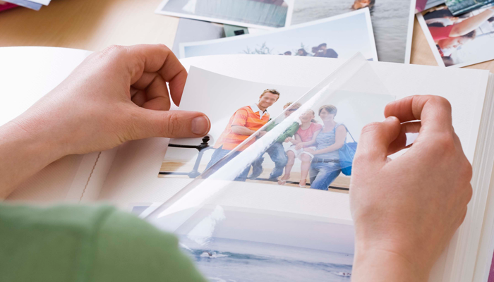 a woman looks through an album, holding a photo of her biological brother from one of his visits